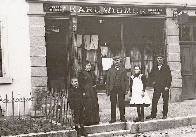 Marie und Karl Widmer-Weisskopf mit ihren Kindern Karl und Julie sowie einem Angestellten vor ihrem Lädeli (um 1910).