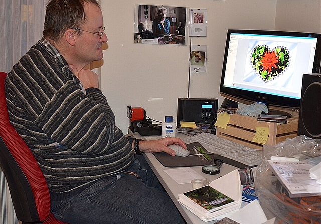Erich Moor an seinem Computer beim Bearbeiten eines Fotos für eine Geschenk-karte (im Vordergrund sieht man einige Karten). Noëlle König)
