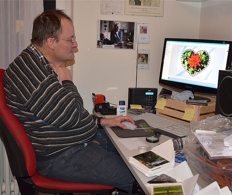 Erich Moor an seinem Computer beim Bearbeiten eines Fotos für eine Geschenk-karte (im Vordergrund sieht man einige Karten). Noëlle König)