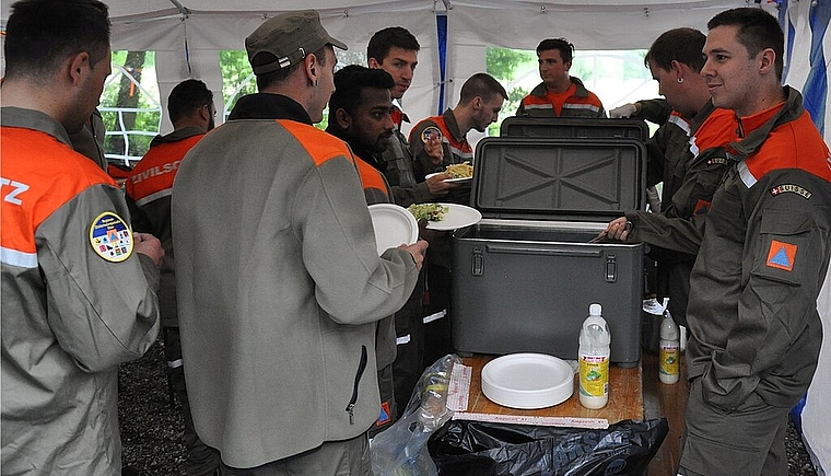 Die Küchenmannschaft (rechts) schöpft das Mittagessen für die Zivilschützer. (Bild: ZVG)