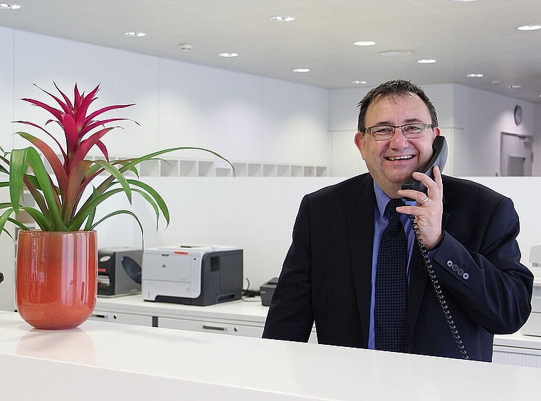 «Grüezi, was chan ich für Sie tue…?», fragt Lucien Meister an seinem Arbeitsplatz, dem Empfang des Kantonspitals Olten, stehend. (Bild: Sonja Furter)