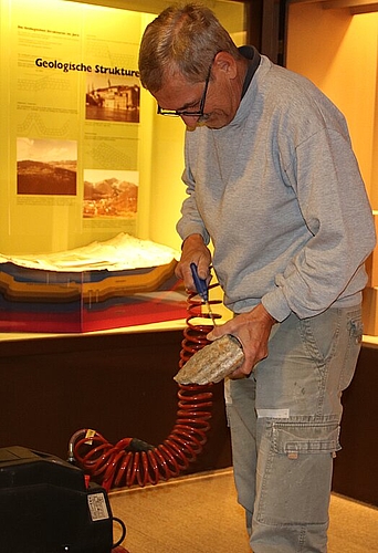 Thomas Imhof reinigt ein Gestein mit einem Gebläse. (Bild: mim)
