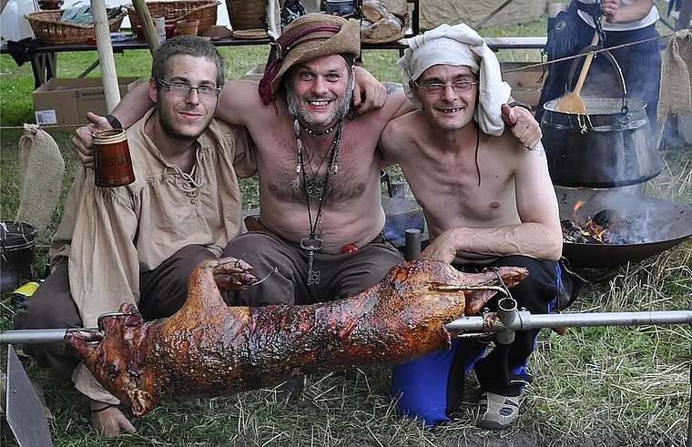 (v.l.) Sämi, «Egalius von Rumpel» und «Bolek von Krakau» beim Zubereiten der traditionellen Spanferkel. ZVG)