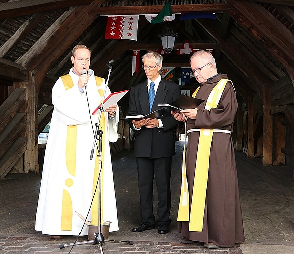 (v.l.) Pfarrer Kai Fehringer der christkatholischen Kirche, Pfarrer Uwe Kaiser der evang.-ref. Kirchgemeinde und Guardian Josef Bründler vom Kapuzinerkloster weihten die neue, alte Holzbrücke mit ihrem Segen und einem Kessel voller Weihwasser. (Bild: mim)
