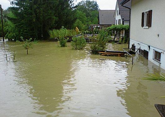 Die Aare hatte ihr Bett verlassen und zog ihre zerstörerischen Bahnen durch Gärten und Gemüsebeete. (Bild: ZVG)
Die Situation am frühen Abend des 8. August 2007. Danach stieg das Wasser noch um fast einen Meter. (Bild: ZVG)
Markus Graber steht im Sommer 2022 trockenen Fusses und durch den Damm im Hintergrund bestens geschützt auf seinem Gartensitzplatz. (Bild: Achim Günter)
Im August 2007 liess sich die selbe Stelle wie oben nur vom Haus aus fotografieren. Im Garten hatte die reissende Aare längst das Zepter übernommen. (Bild: ZVG)